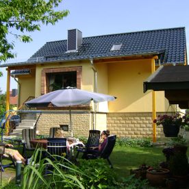 gelbes Haus mit schwarzem Dach und Veranda, Projekt von Dachbau-Meisterbetrieb Wöllner