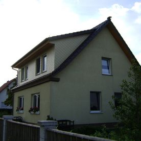 Haus mit Dachvorsprung und Schrägdach, gelbes Haus mit schwarzem Dach und Veranda, Projekt von Dachbau-Meisterbetrieb Wöllner