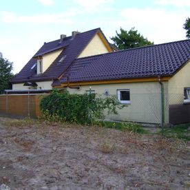 Haus mit Anbau und dunklem Schrägdach, gelbes Haus mit schwarzem Dach und Veranda, Projekt von Dachbau-Meisterbetrieb Wöllner