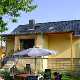 gelbes Haus mit schwarzem Dach und Terrasse, Projekt von Dachbau-Meisterbetrieb Wöllner