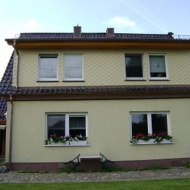 Seitenansicht Haus mit acht Fenstern, gelbes Haus mit schwarzem Dach und Veranda, Projekt von Dachbau-Meisterbetrieb Wöllner